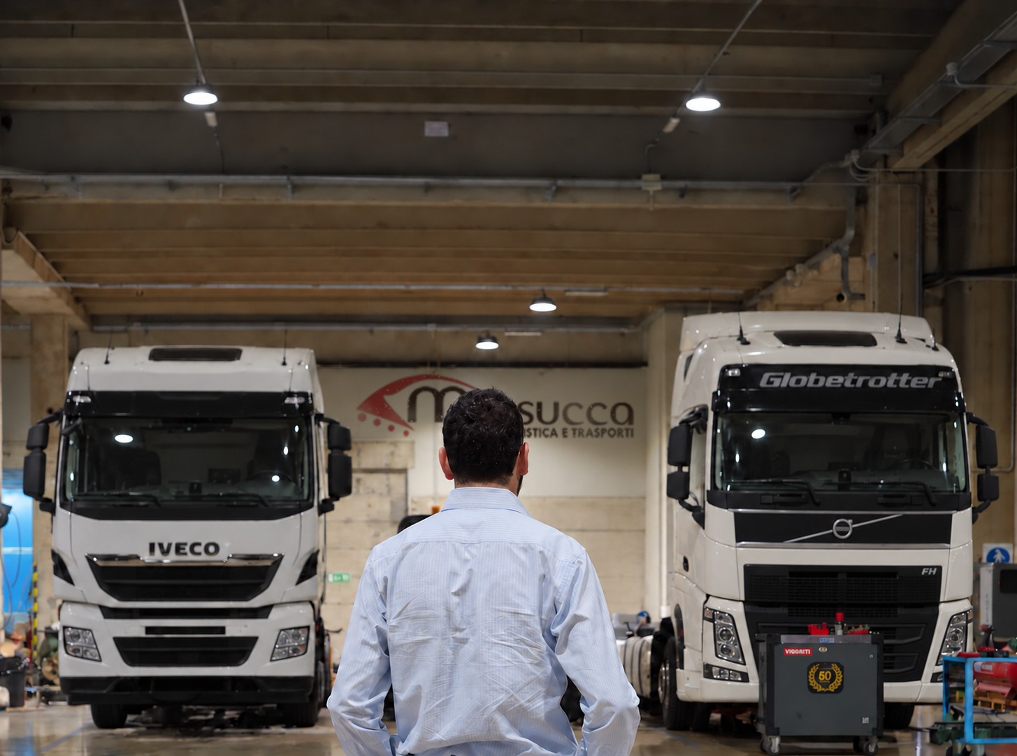 Consulente Mossucca in officina davanti a un Iveco e a un Volvo FH Globetrotter - vendita e noleggio veicoli aziendali